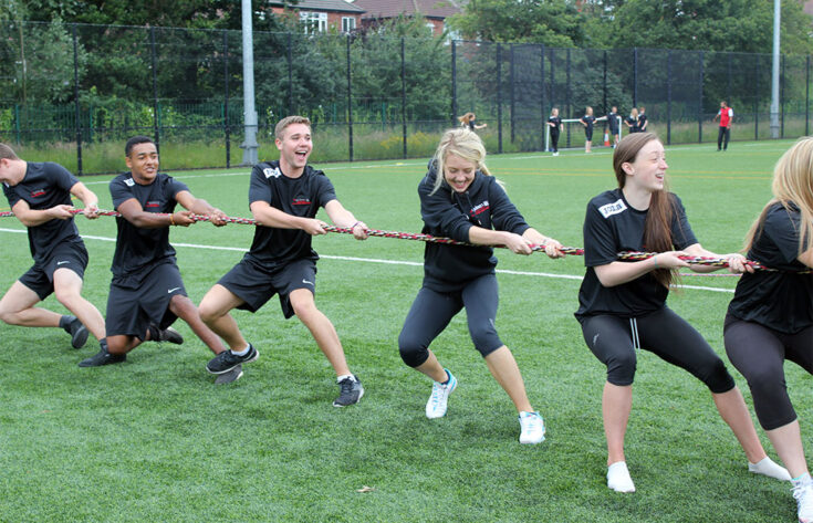 Photograph of students pulling a rope in the sports field.